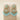 A pair of ornate gold-toned statement earrings with turquoise blue stones and bead drops, displayed on a beige jewelry stand against a warm cream background.
